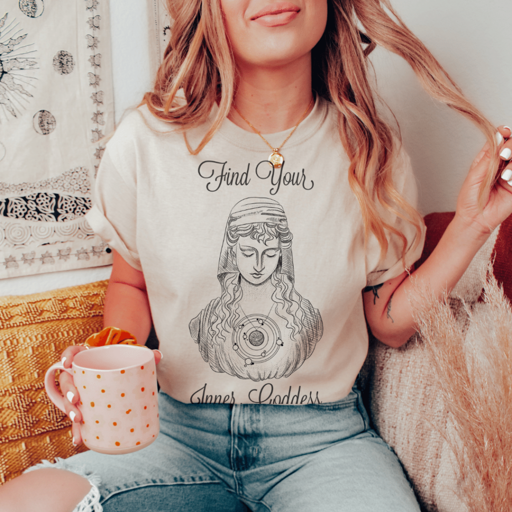 find your inner goddess shirt with woman model sitting in a chair, twirling her hair and hold a mug | Busy Life Healthy Wife | witchy tshirts