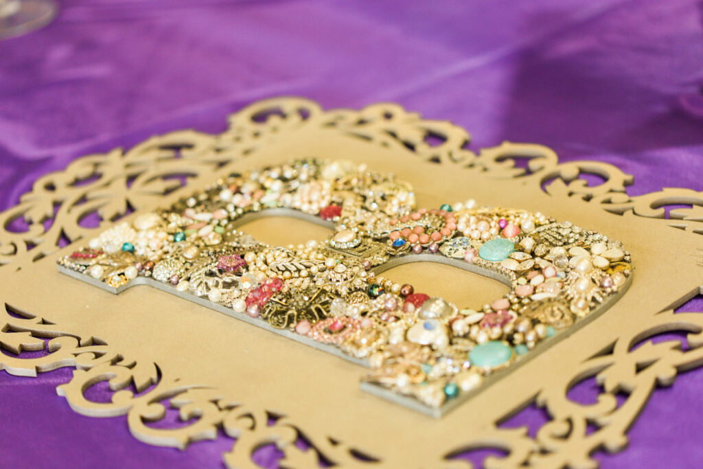 A large B on a stylized board. The B has a mix of antique jewelry, gemstones, and filigree glued onto the B to make it a gorgeous statement piece for a wedding or home. It is lying on a purple table cloth | | Busy Life Healthy Wife - Holistically create marketing that's effortlessly woowoo, effortlessly you